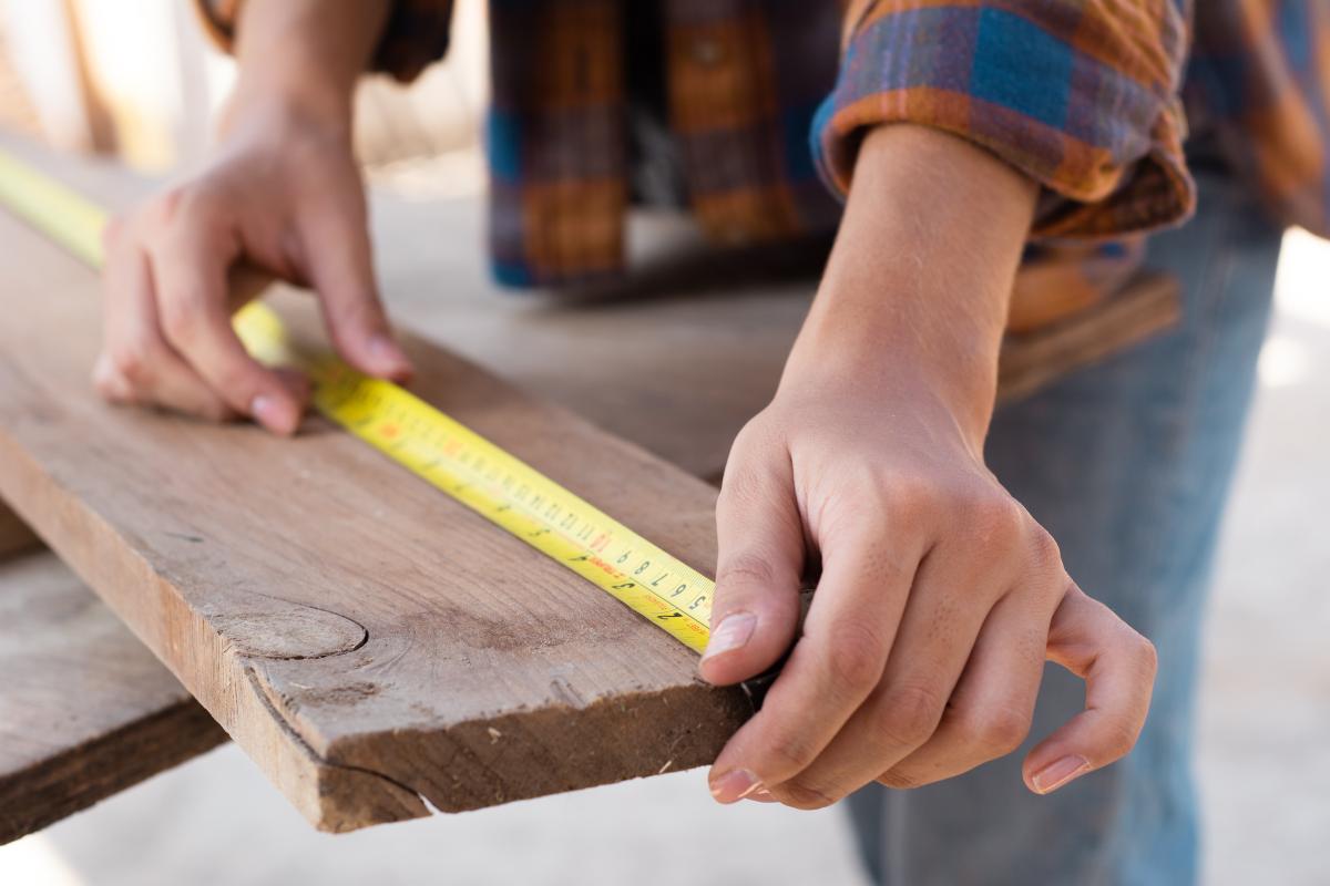 Craftsman measuring wood for precision manufacturing